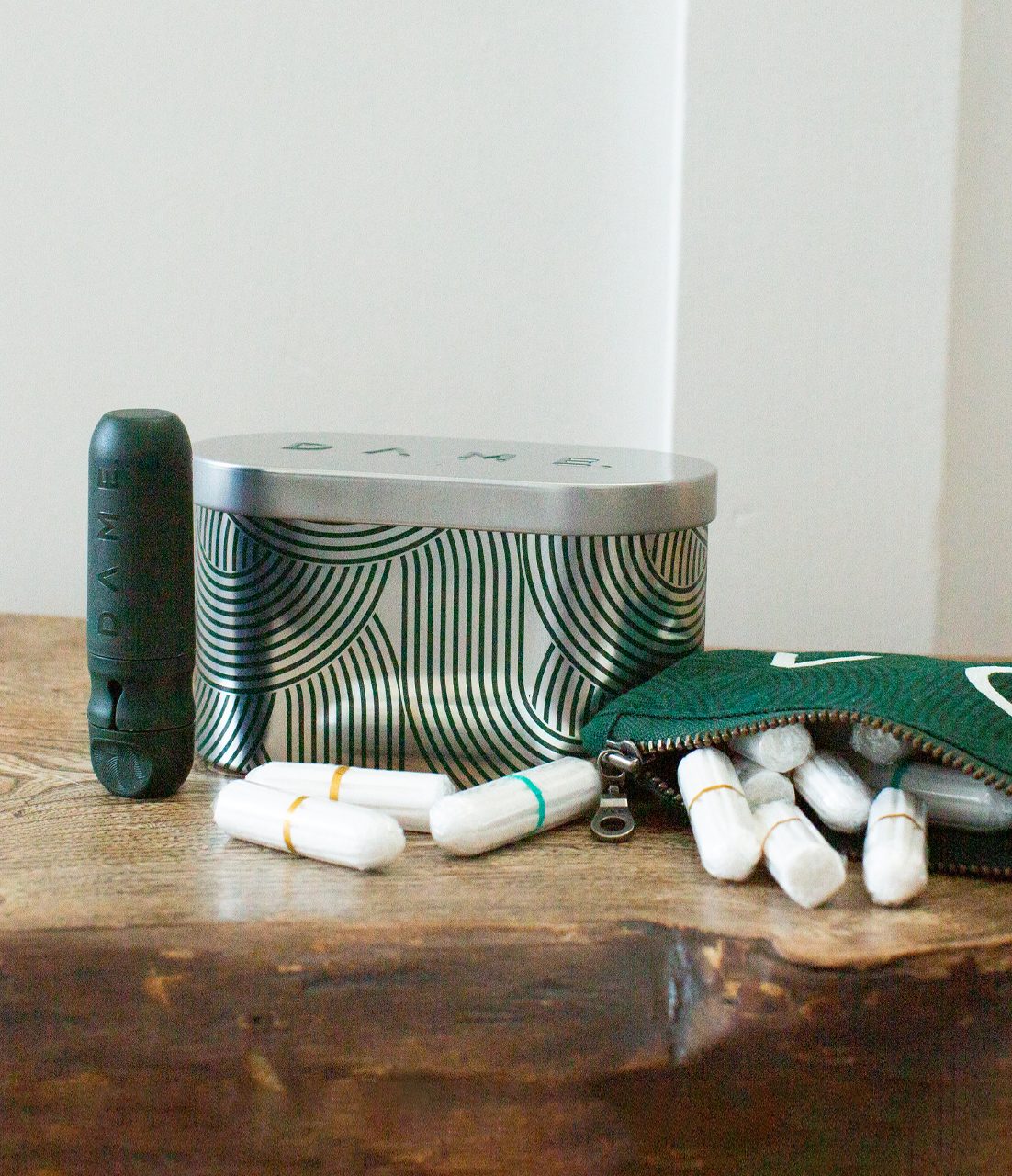 Boîte à pilules verte avec capsules blanches et un tube vert à côté.