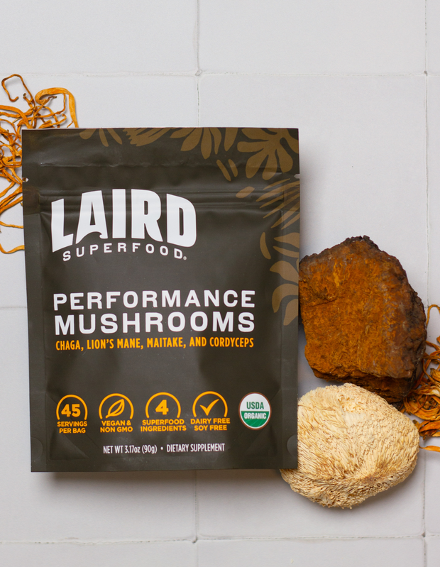Une main ajoute de la poudre dans une tasse, avec un sachet de crème superalimentaire en arrière-plan bio laird superfood 