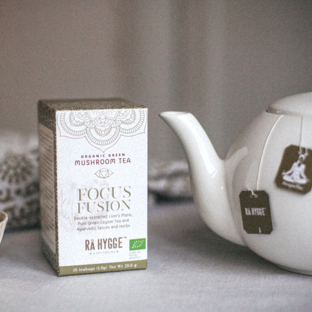 Thé en boîte "Focus Fusion" à côté d'une théière blanche.