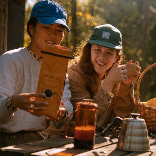 Deux personnes souriantes, préparant du café bio champignon en pleine nature.