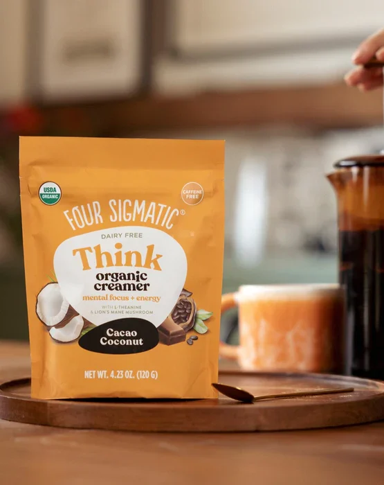 Sachet de café Think, goût caramel, sur une table en bois avec une tasse à côté.